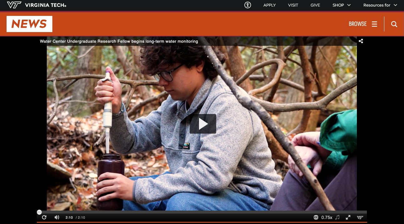 Jesse takes a water sample from a stream in a wooded area. 